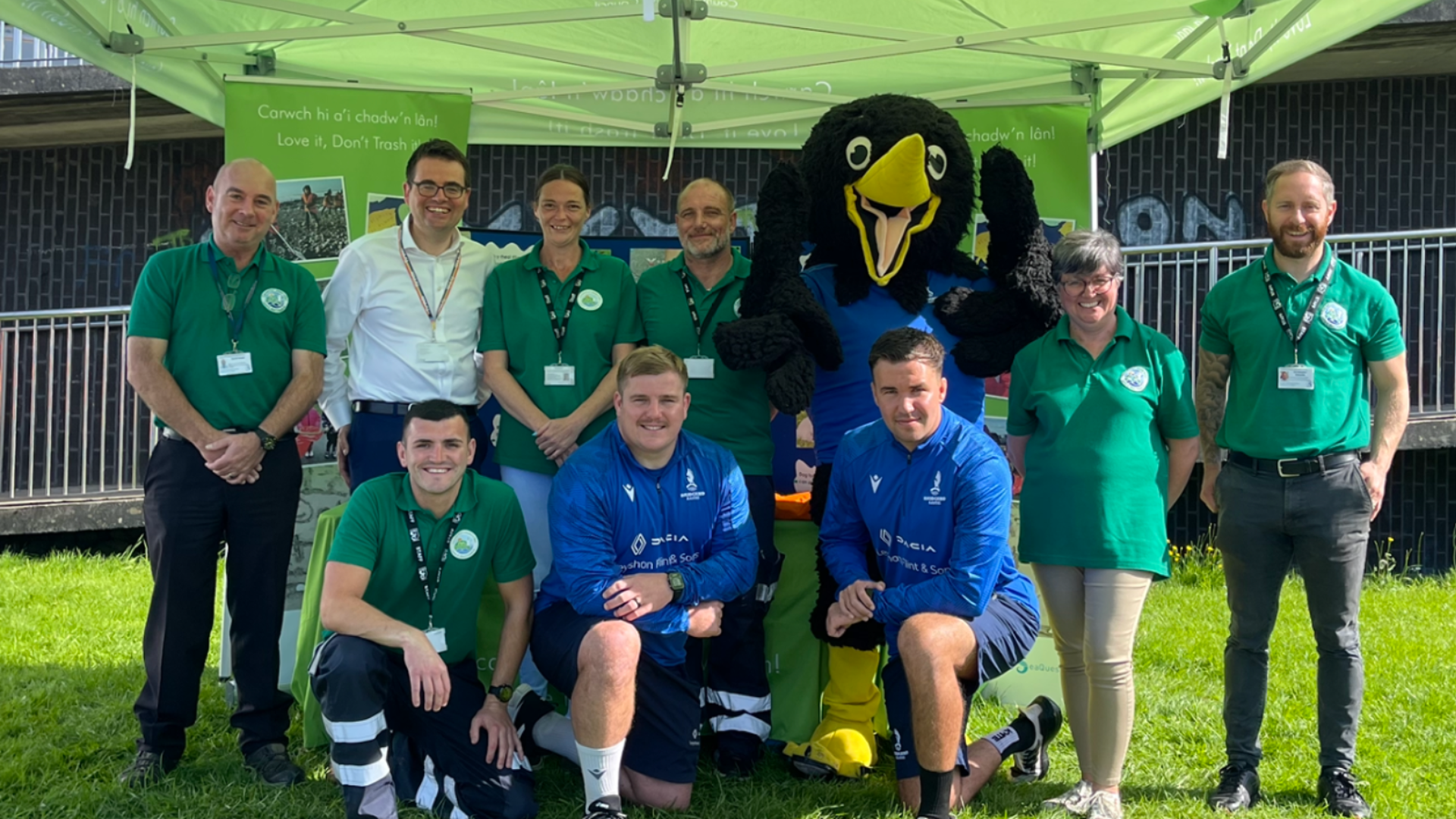 The council’s Dog Fouling Engagement Team with the Council Leader Huw David, Bridgend Ravens Club Mascot Ronnie the Raven, and Bridgend Ravens Team Members Aled Evans and Evan Yardley at Newbridge Fields, Bridgend.