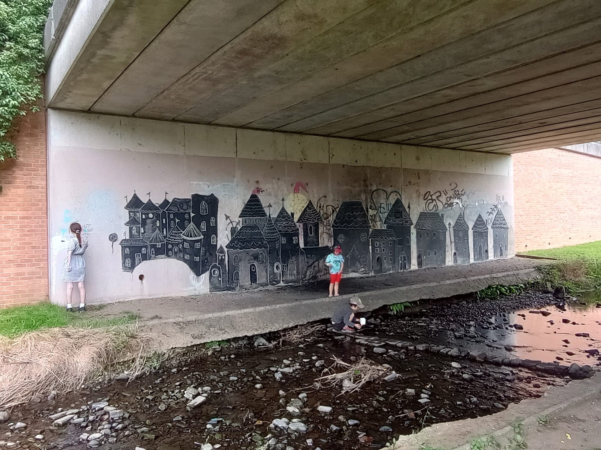 The underpass with graffiti being painted over with a picture of fairy tale houses