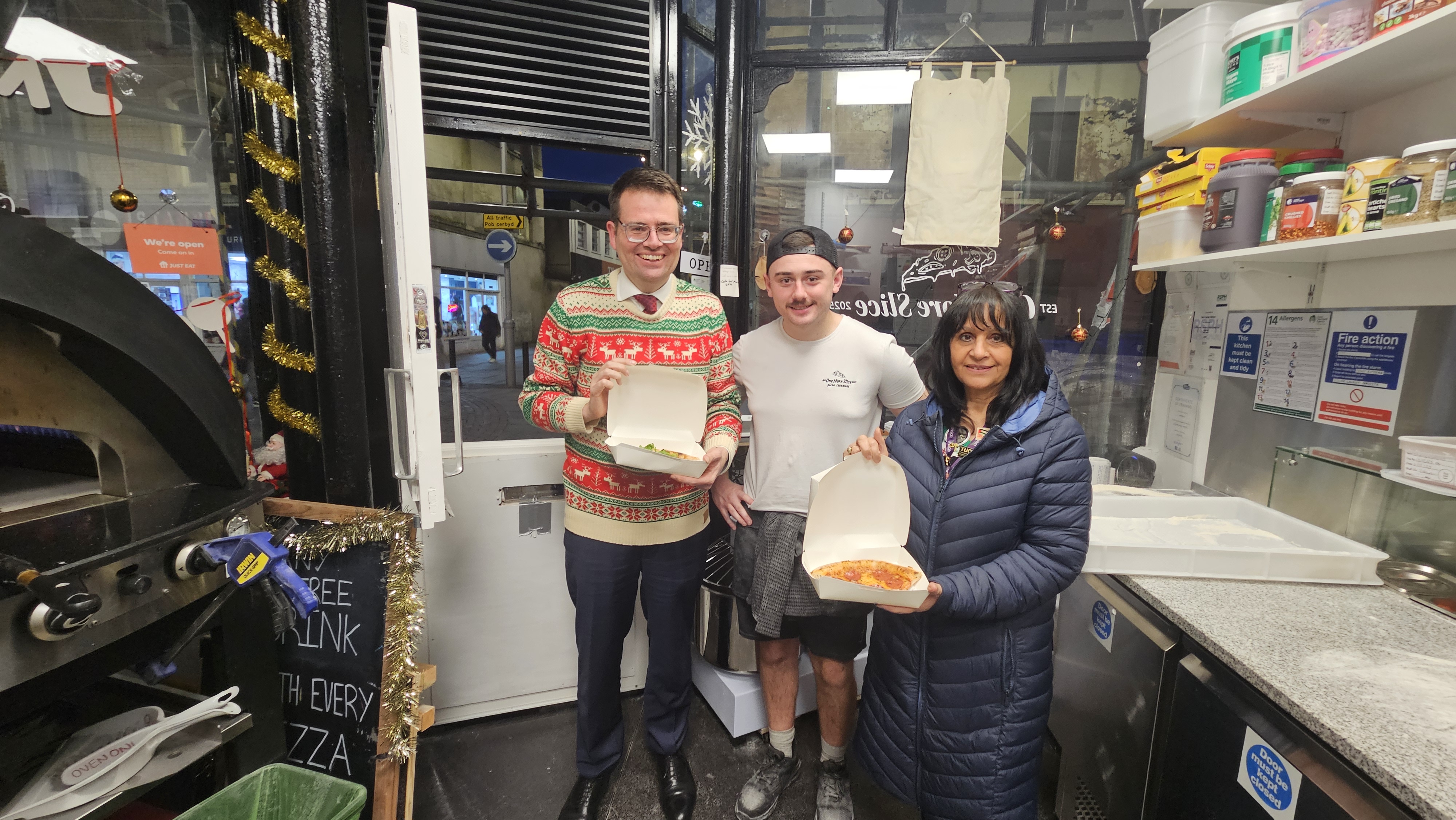 (L-R) Councillor Huw David, Mayor of Bridgend County Borough, Alec Gilmore, owner of One More Slice and Councillor Neelo Farr, Cabinet Member for Regeneration, Economic Development and Housing at the new pizzeria unit in Wyndham Street.