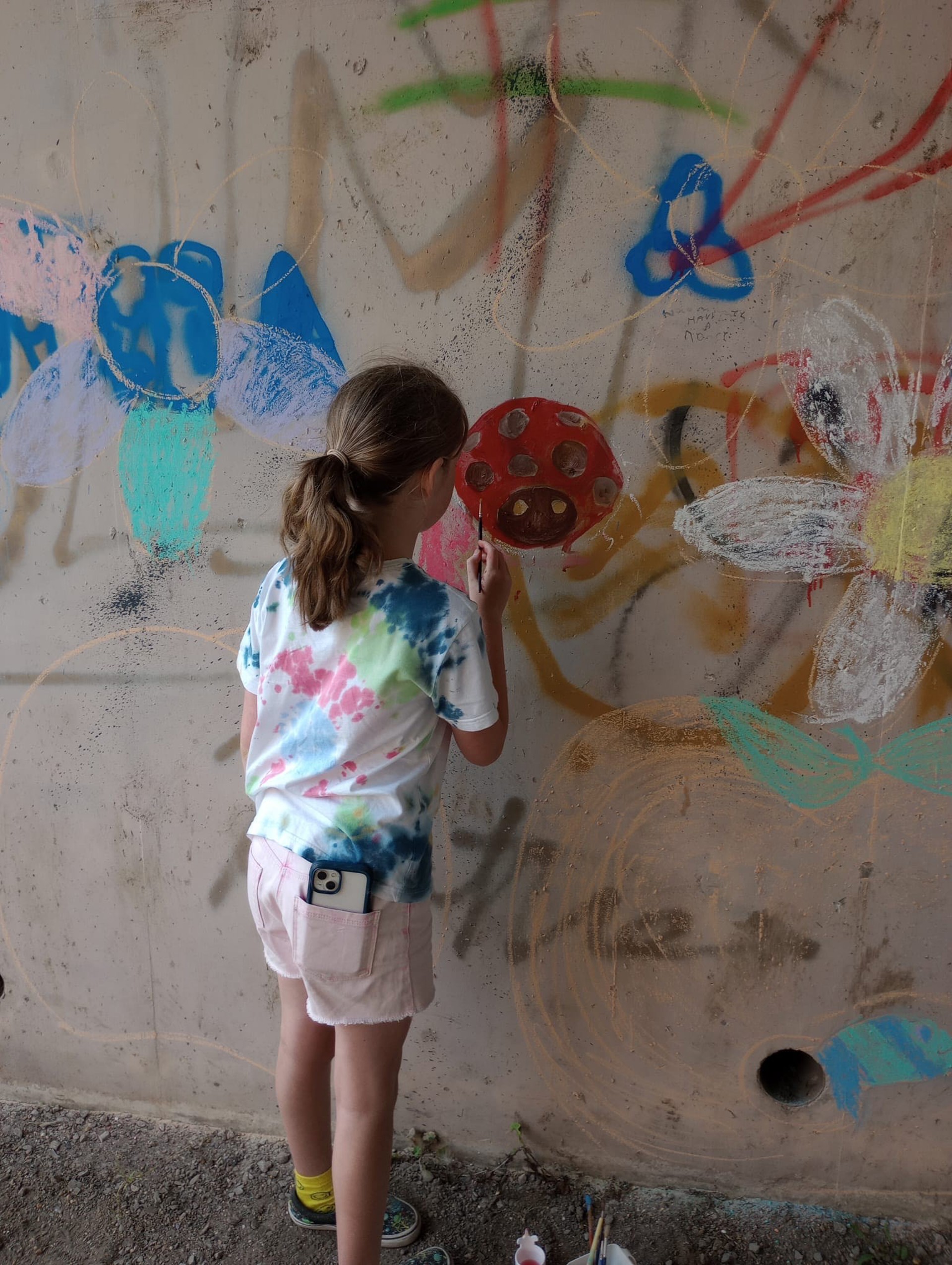The underpass with graffiti being painted over with a picture of a ladybird