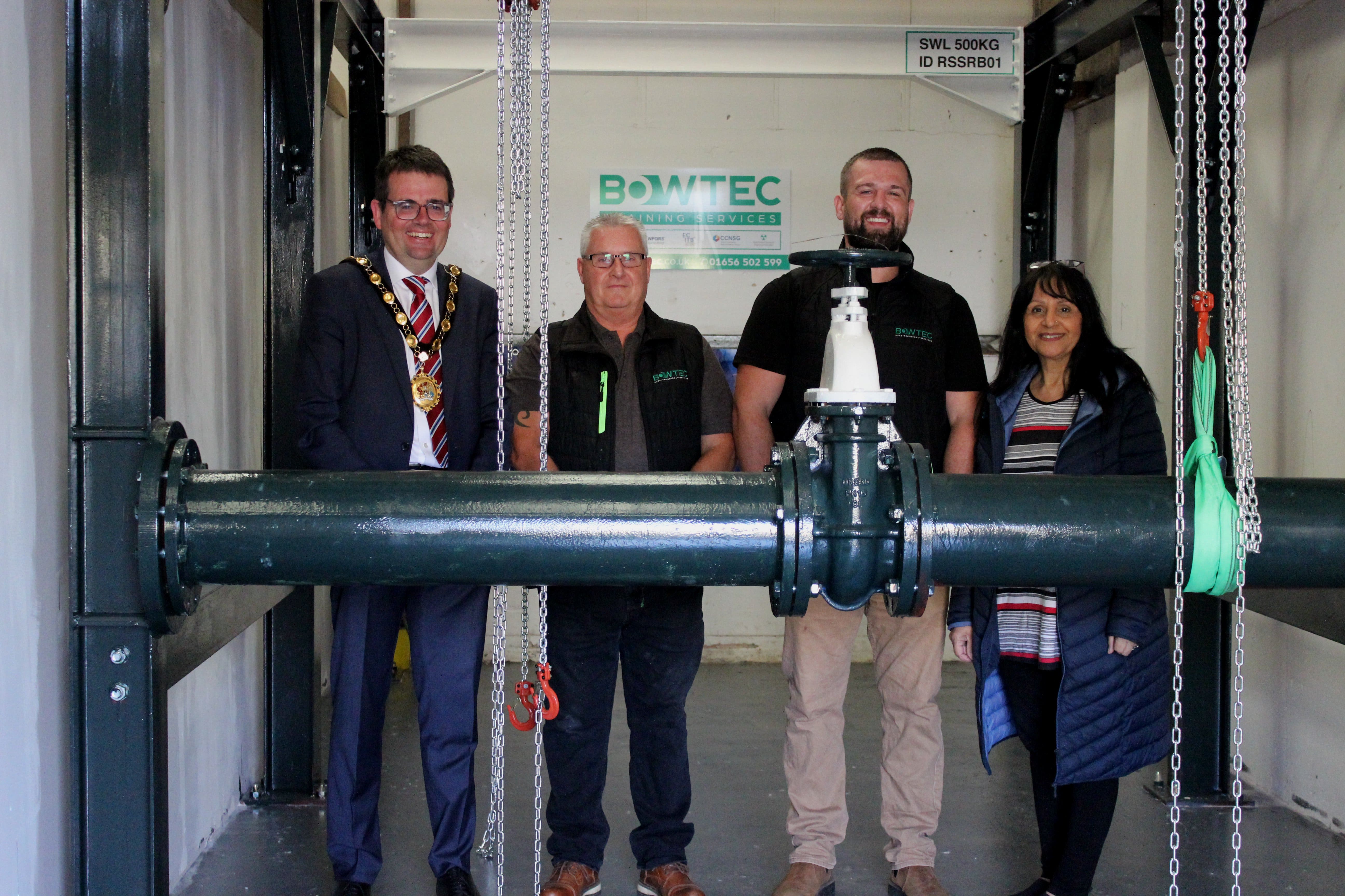 (L-R) Councillor Huw David, Mayor of Bridgend County Borough, Paul, Callum, and Councillor Neelo Farr, Cabinet Member for Regeneration, Economic Development and Housing stood by the new bespoke rig at Bowtec’s training centre in Pyle.